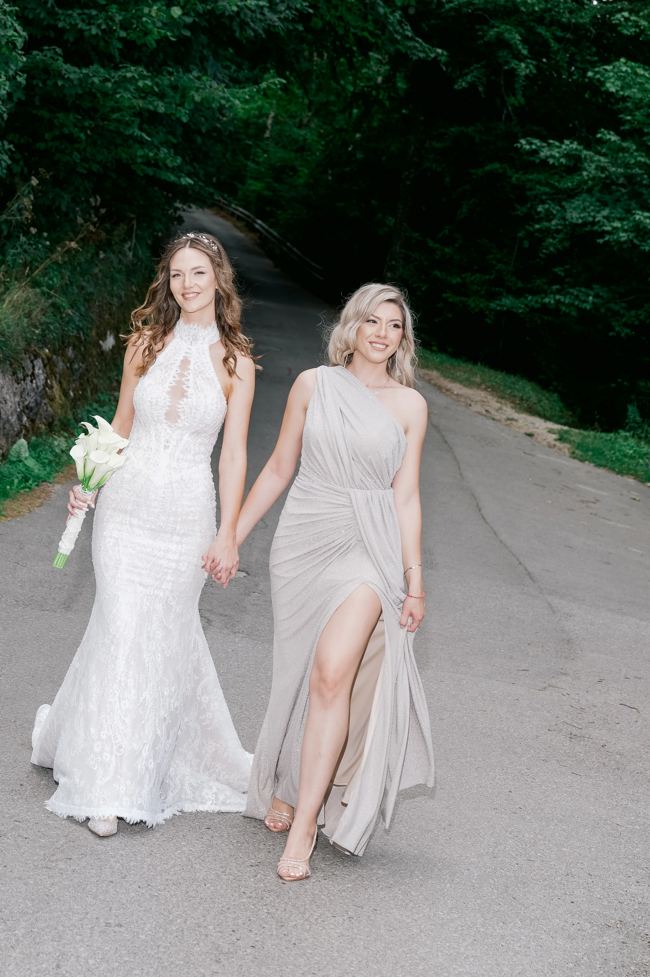 Bride walking with her bridesmaid on a forest road